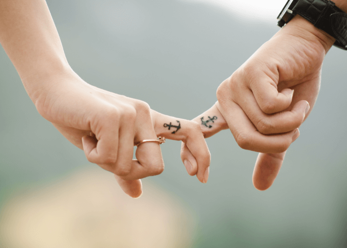 2 partners holding hands with couple tattoo